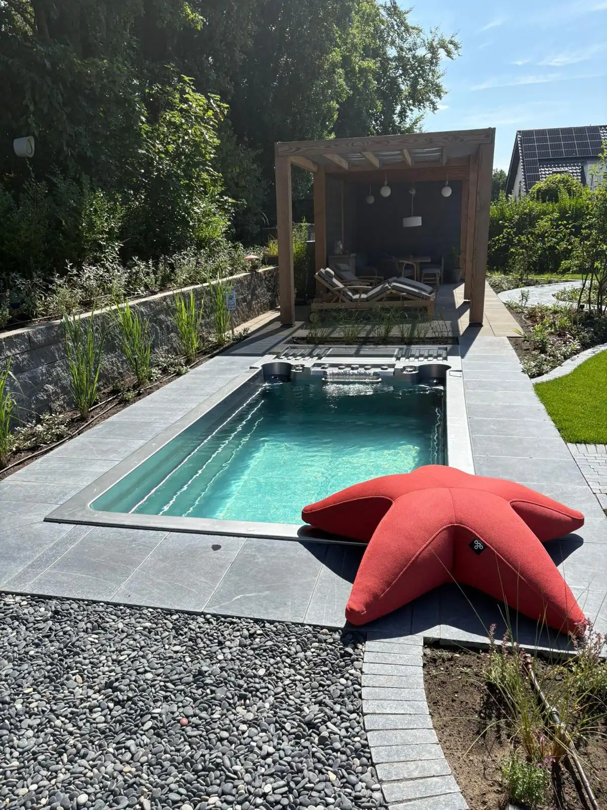 INFINITAS swim spa fully inground in a garden with pergola