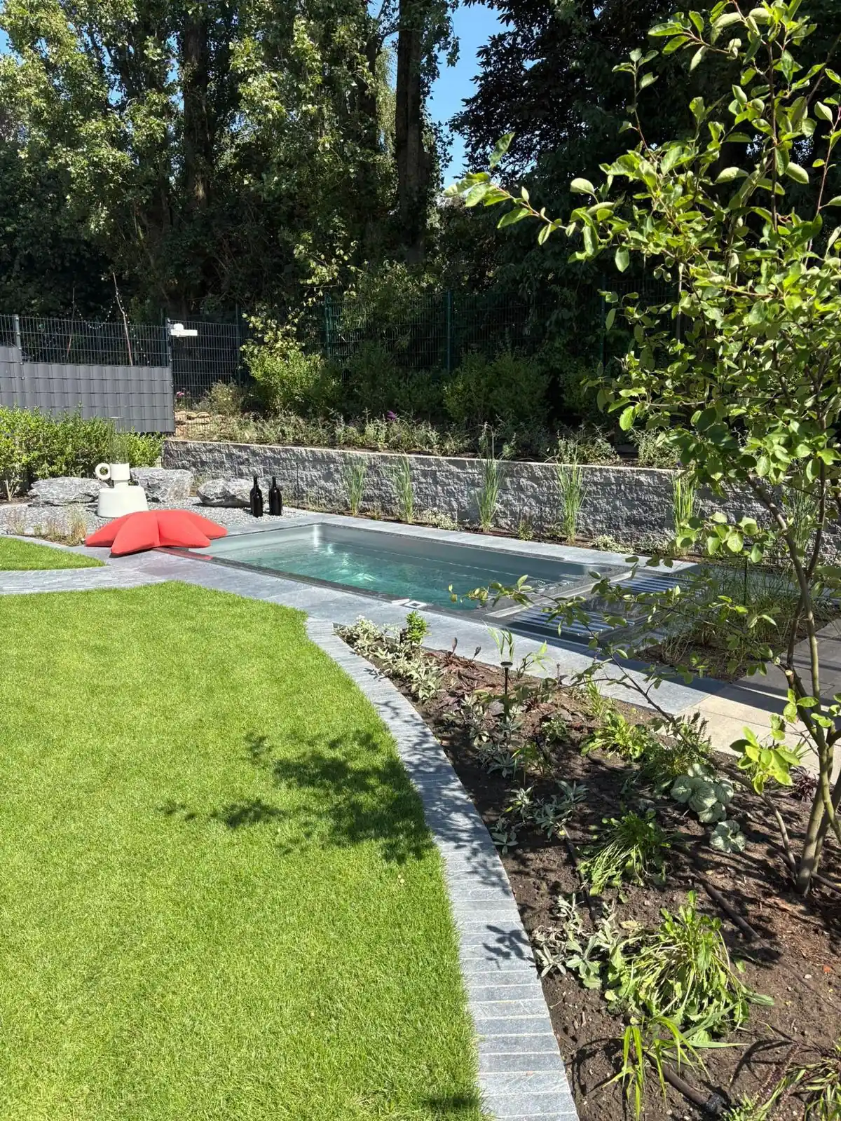INFINITAS swim spa fully inground in a garden, flush with lawn and paving